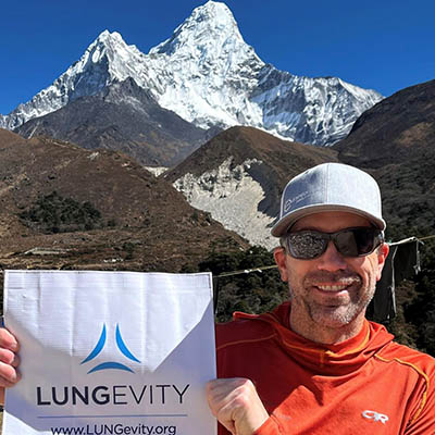 Jay Mathers in the Himalayas holding a LUNGevity banner