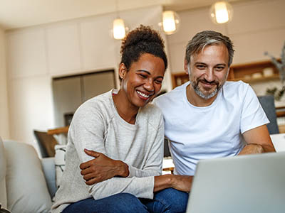 A couple sitting together in front of a laptop