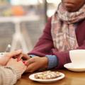 Two people supportively holding hands over coffee table