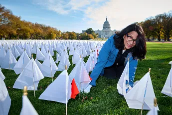 Woman kneeling in field of flags