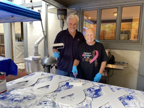 Bill and Betty Moren smiling while painting white ribbons for lung cancer awareness