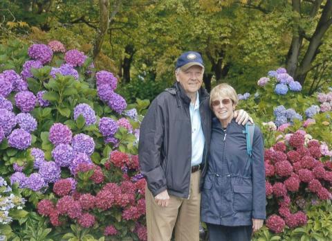 Tom and Mary Lynn smiling with blooming flowers behind them